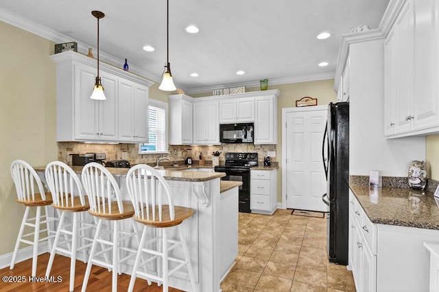 421 30th St, Sunset Beach, NC 28468 - kitchen featuring black appliances, a breakfast bar area, a peninsula, white cabinets, and tasteful backsplash