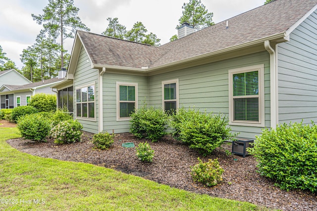 255 Champions Ridge Dr, Southern Pines, NC 28387 - view of side of property featuring a chimney, a yard, cooling unit, and a shingled roof