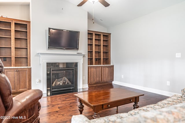 255 Champions Ridge Dr, Southern Pines, NC 28387 - living area with a ceiling fan, dark wood-style floors, vaulted ceiling, a glass covered fireplace, and baseboards