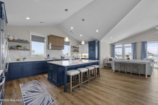 145 Oceanview Ln, North Topsail Beach, NC 28460 - kitchen featuring open shelves, blue cabinets, vaulted ceiling, a kitchen bar, and light countertops