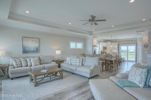 876-878 Villas Dr, North Topsail Beach, NC 28460 - living room with light wood-style floors, a raised ceiling, recessed lighting, a ceiling fan, and crown molding