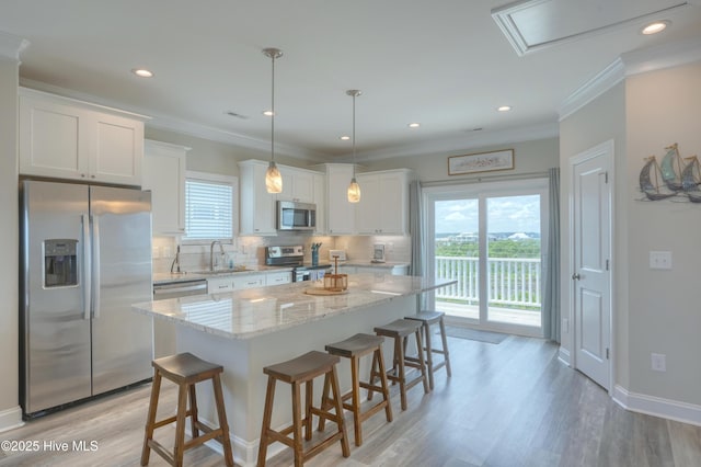 876-878 Villas Dr, North Topsail Beach, NC 28460 - kitchen featuring appliances with stainless steel finishes, tasteful backsplash, a kitchen breakfast bar, white cabinetry, and a center island