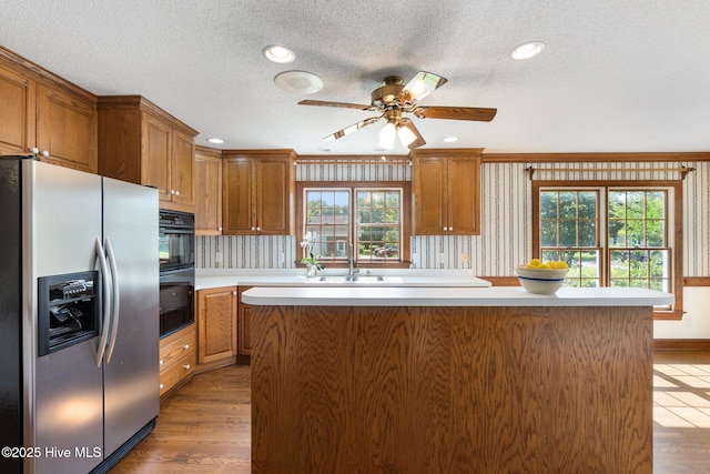 116 Spencer Ln, Newport, NC 28570 - kitchen featuring stainless steel refrigerator with ice dispenser, light countertops, brown cabinetry, a center island, and a ceiling fan