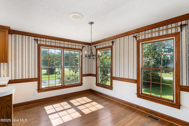 116 Spencer Ln, Newport, NC 28570 - unfurnished dining area with a chandelier, a textured ceiling, wood finished floors, and wallpapered walls