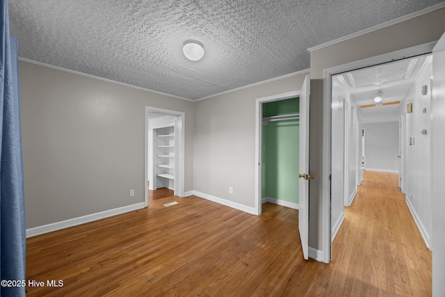 2411 Grace Ave, New Bern, NC 28562 - unfurnished bedroom with attic access, wood finished floors, a closet, a textured ceiling, and a walk in closet