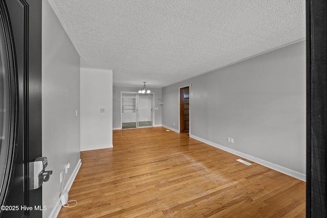 2411 Grace Ave, New Bern, NC 28562 - spare room featuring a chandelier, a textured ceiling, light wood-type flooring, and baseboards