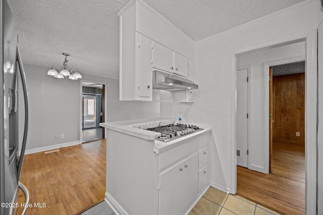 2411 Grace Ave, New Bern, NC 28562 - kitchen with stainless steel appliances, under cabinet range hood, a textured ceiling, white cabinetry, and a chandelier