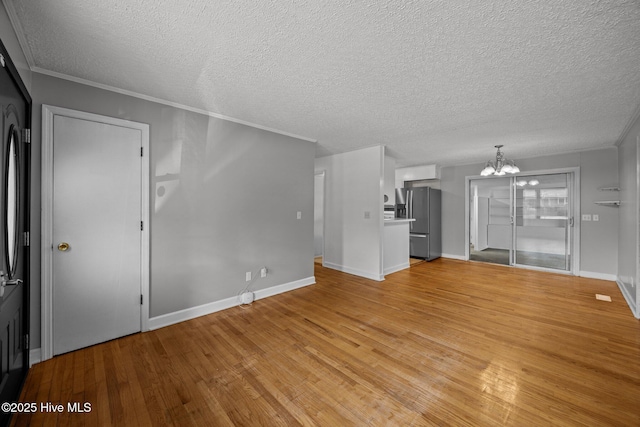 2411 Grace Ave, New Bern, NC 28562 - unfurnished living room with a chandelier, a textured ceiling, light wood-style floors, baseboards, and ornamental molding