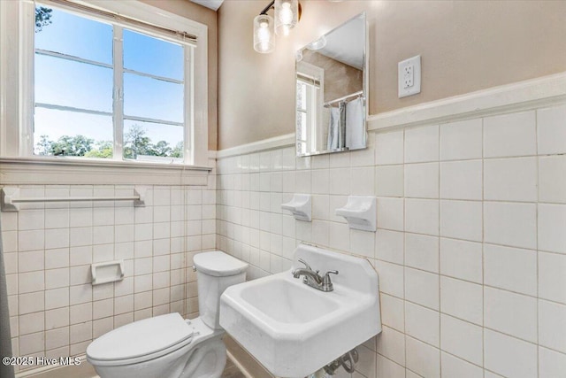 403 S Andrews Ave, Goldsboro, NC 27530 - bathroom with toilet, tile walls, a sink, a wainscoted wall, and a shower with curtain