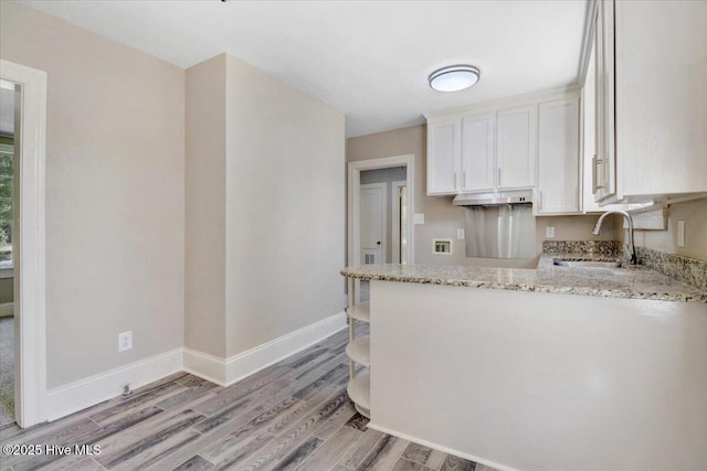 403 S Andrews Ave, Goldsboro, NC 27530 - kitchen with a sink, light stone countertops, white cabinets, light wood-style flooring, and a peninsula