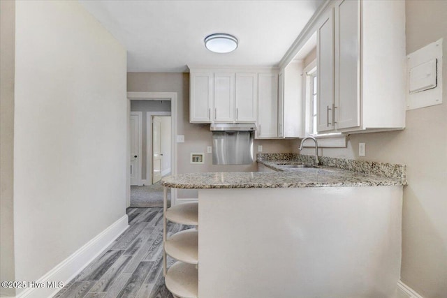 403 S Andrews Ave, Goldsboro, NC 27530 - kitchen with a sink, baseboards, light stone counters, and light wood-style flooring