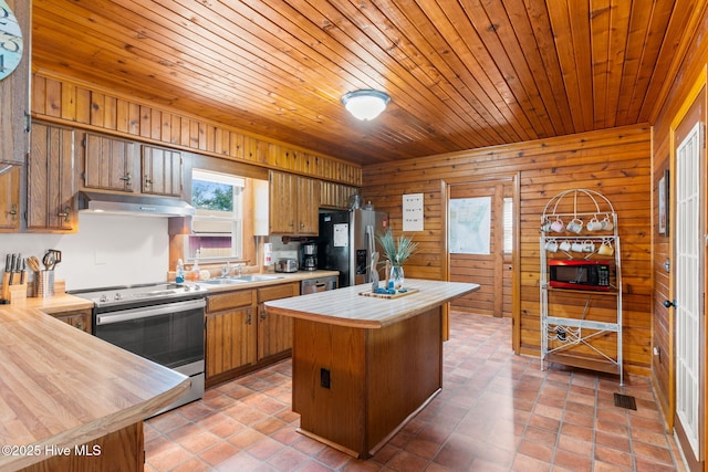 103 NE 17th St, Oak Island, NC 28465 - kitchen with stainless steel appliances, under cabinet range hood, wood walls, a center island, and butcher block counters
