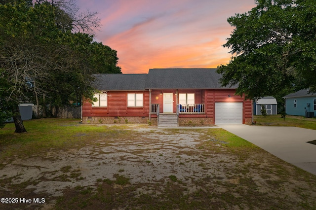103 NE 17th St, Oak Island, NC 28465 - view of front facade with a shingled roof, driveway, a garage, a porch, and central AC
