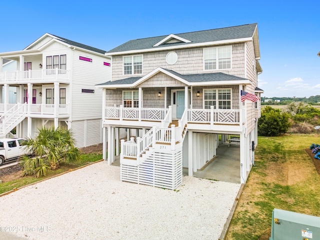 271 E Second St, Ocean Isle Beach, NC 28469 - coastal inspired home with a carport, a porch, stairs, and gravel driveway