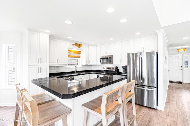 271 E Second St, Ocean Isle Beach, NC 28469 - kitchen featuring appliances with stainless steel finishes, light wood-type flooring, white cabinetry, a breakfast bar area, and recessed lighting