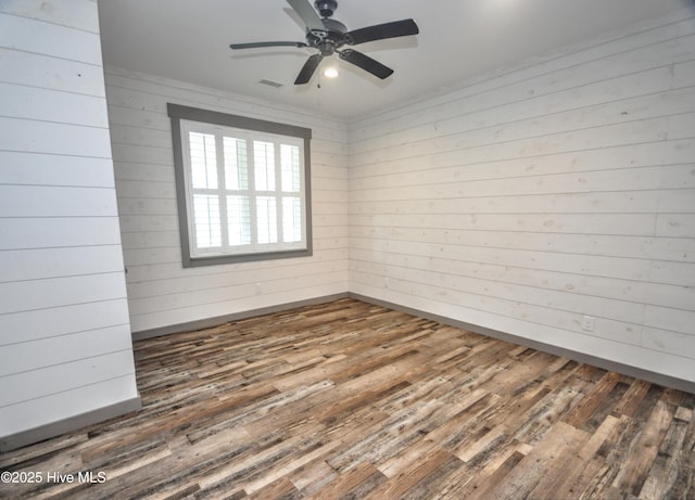 9265 W Lake Rd, Calabash, NC 28467 - spare room featuring dark wood-style flooring, ceiling fan, wooden walls, and baseboards