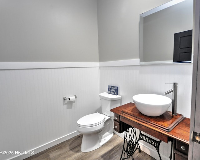 9265 W Lake Rd, Calabash, NC 28467 - half bathroom featuring a sink, wainscoting, wood finished floors, and toilet