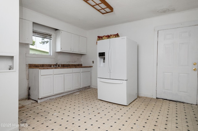 926 Cedar St, New Bern, NC 28560 - kitchen featuring white fridge with ice dispenser, white cabinetry, dark countertops, and light flooring