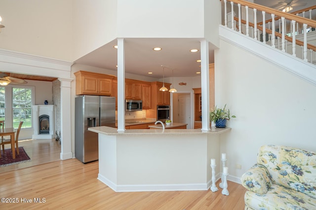 3399 Channelside Dr SW, Supply, NC 28462 - kitchen featuring stainless steel appliances, ceiling fan, light wood-style floors, a towering ceiling, and a peninsula