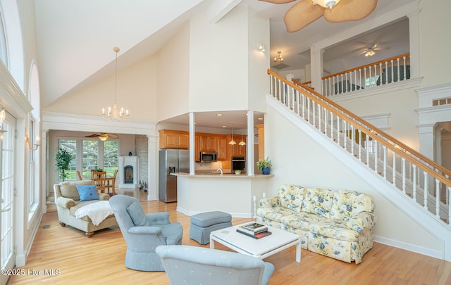 3399 Channelside Dr SW, Supply, NC 28462 - living room with a ceiling fan, a high ceiling, a fireplace with raised hearth, light wood-type flooring, and stairway