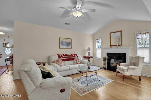 111 Bay Tree Cir, Hampstead, NC 28443 - living area featuring vaulted ceiling, ceiling fan, light wood finished floors, a glass covered fireplace, and baseboards