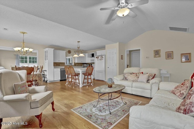 111 Bay Tree Cir, Hampstead, NC 28443 - living area with a chandelier, a ceiling fan, vaulted ceiling, light wood finished floors, and a textured ceiling
