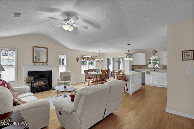 111 Bay Tree Cir, Hampstead, NC 28443 - living area featuring ceiling fan, light wood-type flooring, a glass covered fireplace, lofted ceiling, and a chandelier