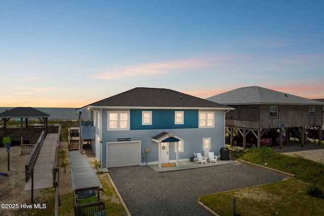 1001 W Beach Dr, Oak Island, NC 28465 - view of front facade featuring a gazebo, stairs, a garage, driveway, and a patio area