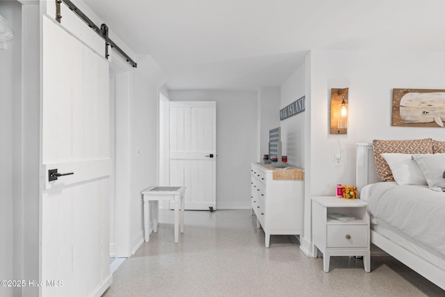 1001 W Beach Dr, Oak Island, NC 28465 - bedroom featuring a barn door, baseboards, and dark speckled floor