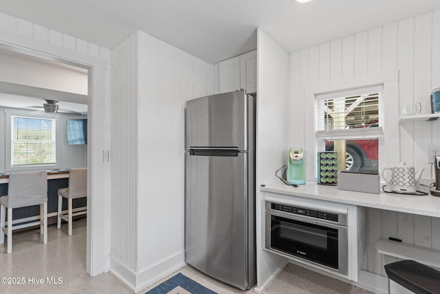 1001 W Beach Dr, Oak Island, NC 28465 - kitchen featuring appliances with stainless steel finishes, light stone countertops, ceiling fan, and white cabinetry