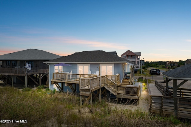 1001 W Beach Dr, Oak Island, NC 28465 - back of property at dusk featuring a wooden deck, roof with shingles, and stairs