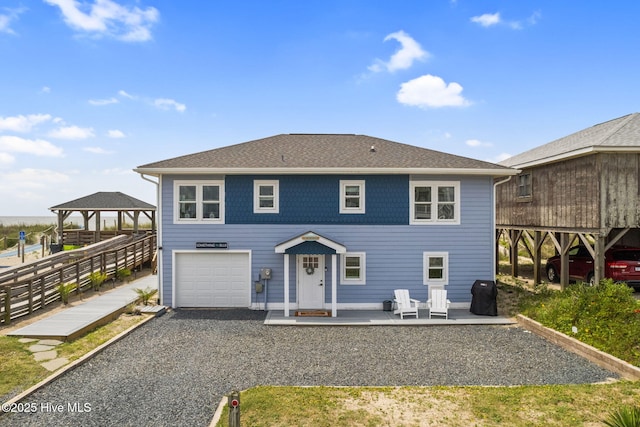 1001 W Beach Dr, Oak Island, NC 28465 - view of front of house featuring a gazebo, an attached garage, gravel driveway, and a shingled roof