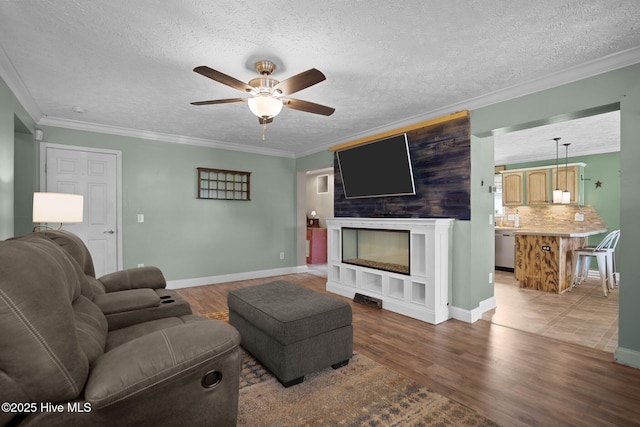 710 Ridgecrest Ln, Rocky Point, NC 28457 - living area featuring ceiling fan, a textured ceiling, wood finished floors, a fireplace, and ornamental molding
