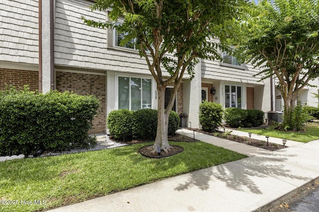 648 Cobblestone Dr, Wilmington, NC 28405 - view of front of house with brick siding, a front lawn, mansard roof, and central air condition unit