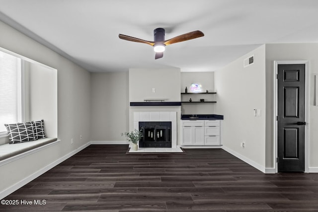 648 Cobblestone Dr, Wilmington, NC 28405 - unfurnished living room with a tiled fireplace, a ceiling fan, dark wood finished floors, and baseboards