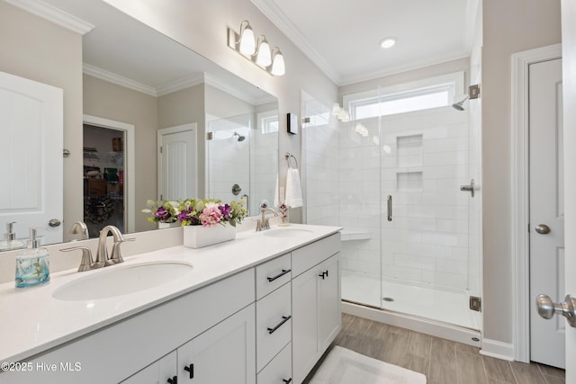 438 Sugar Cove Run, Wilmington, NC 28411 - bathroom featuring a stall shower, double vanity, a spacious closet, crown molding, and wood finished floors
