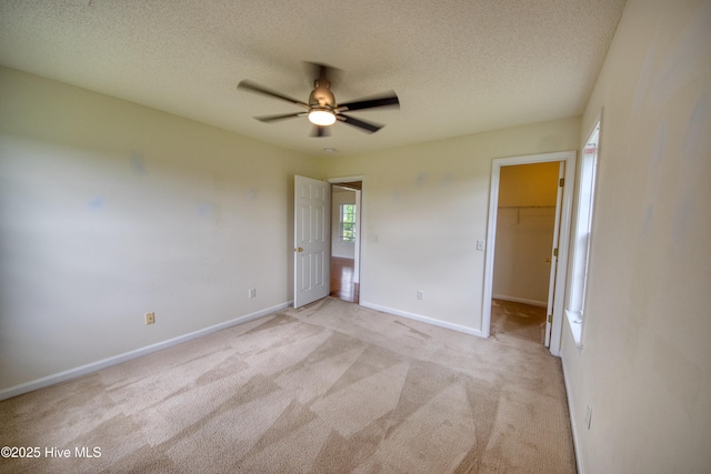 7308 Peppercorn Ct, Wilmington, NC 28411 - unfurnished bedroom with a textured ceiling, light carpet, a walk in closet, baseboards, and a ceiling fan