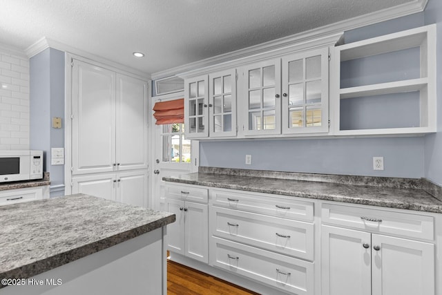 1205 Logan Ct, Jacksonville, NC 28540 - kitchen with ornamental molding, white microwave, white cabinets, glass insert cabinets, and a textured ceiling