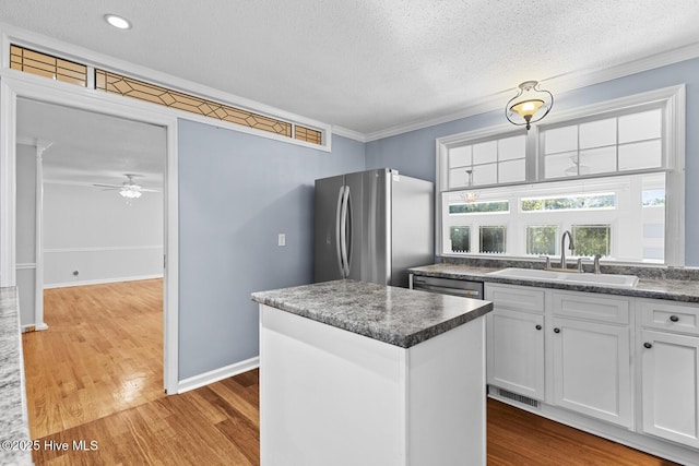 1205 Logan Ct, Jacksonville, NC 28540 - kitchen with appliances with stainless steel finishes, a sink, a textured ceiling, white cabinets, and wood finished floors
