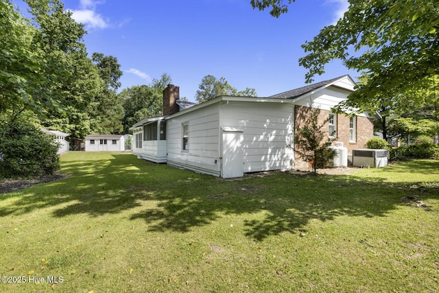 1205 Logan Ct, Jacksonville, NC 28540 - back of house with a chimney, a lawn, and brick siding
