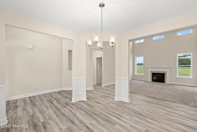 411 Fore Pl, Jacksonville, NC 28540 - unfurnished living room featuring light wood finished floors, a chandelier, healthy amount of natural light, and a fireplace with flush hearth
