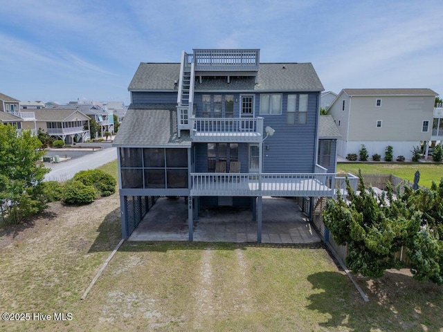 308 N Shore Dr E, Sunset Beach, NC 28468 - back of house featuring roof with shingles, a sunroom, a yard, a balcony, and driveway
