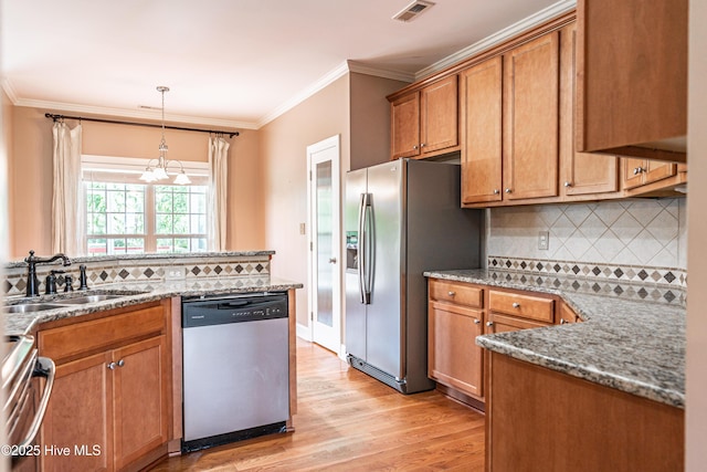 600 Booth Pond Rd, Raeford, NC 28376 - kitchen featuring appliances with stainless steel finishes, a sink, brown cabinetry, a chandelier, and ornamental molding