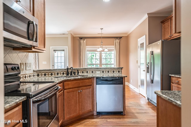 600 Booth Pond Rd, Raeford, NC 28376 - kitchen with stainless steel appliances, brown cabinets, a sink, light wood-style flooring, and decorative backsplash