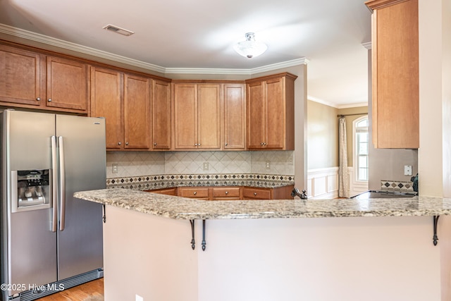 600 Booth Pond Rd, Raeford, NC 28376 - kitchen with stainless steel fridge, a peninsula, crown molding, light stone counters, and brown cabinetry