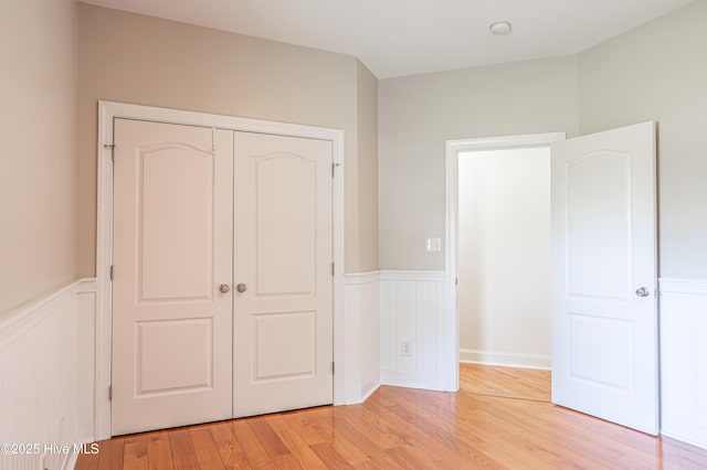 600 Booth Pond Rd, Raeford, NC 28376 - unfurnished bedroom with a wainscoted wall, light wood finished floors, a closet, and a decorative wall