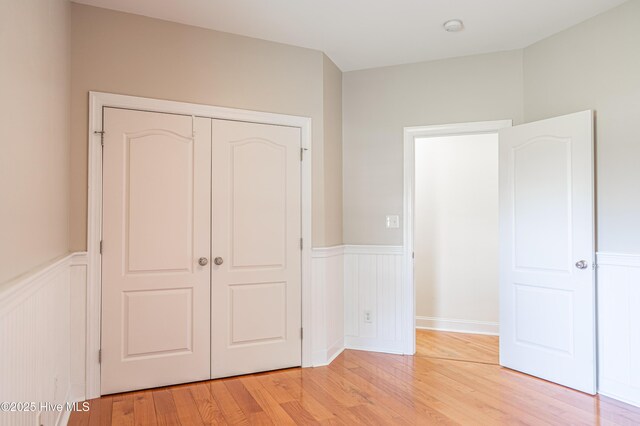 600 Booth Pond Rd, Raeford, NC 28376 - unfurnished bedroom with a wainscoted wall, light wood finished floors, a closet, and a decorative wall