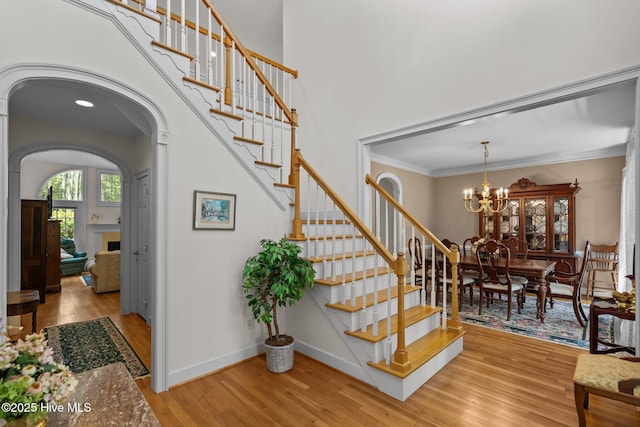6304 Wolfhead Ct, Wilmington, NC 28411 - stairway featuring wood finished floors, arched walkways, a chandelier, baseboards, and ornamental molding