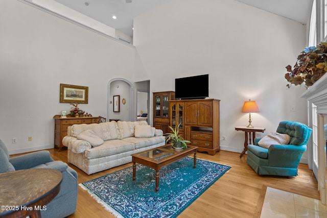 6304 Wolfhead Ct, Wilmington, NC 28411 - living area with arched walkways, a towering ceiling, baseboards, light wood finished floors, and recessed lighting