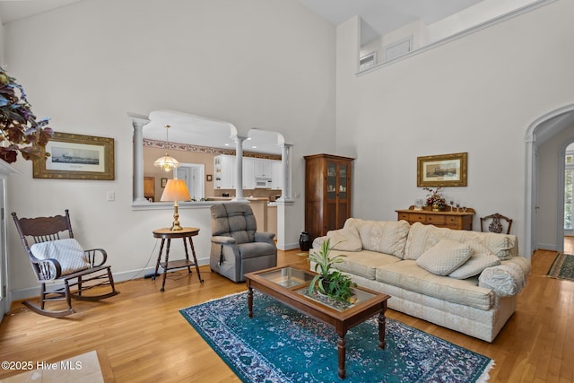 6304 Wolfhead Ct, Wilmington, NC 28411 - living area featuring arched walkways, wood finished floors, a towering ceiling, baseboards, and decorative columns